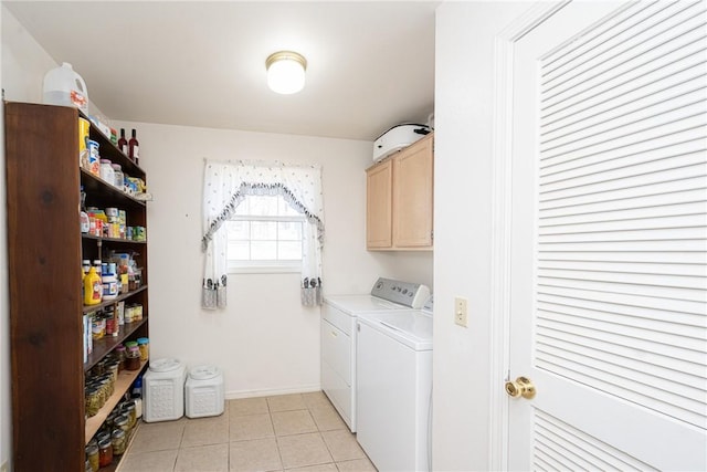 washroom with light tile patterned floors, baseboards, cabinet space, and washer and clothes dryer