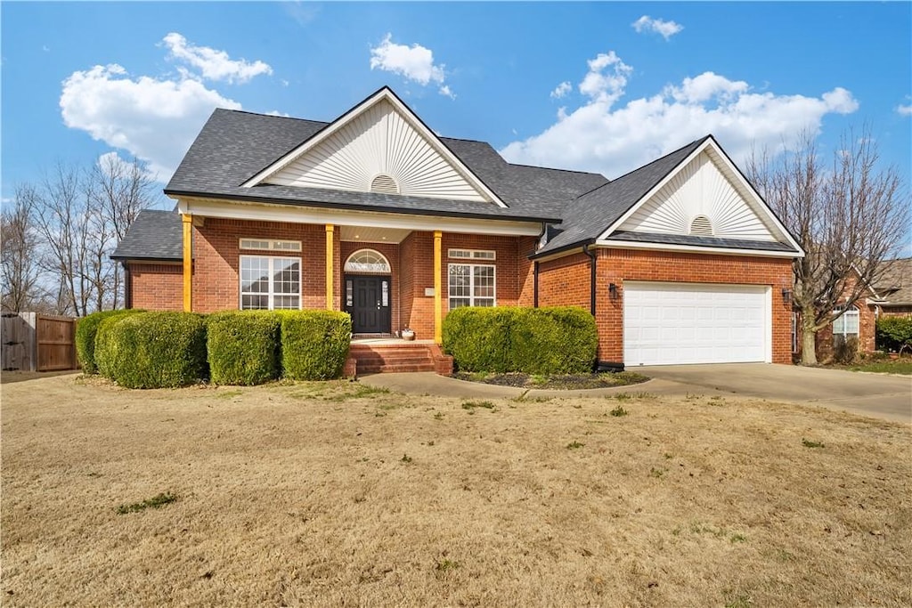 view of front facade with brick siding, an attached garage, a shingled roof, fence, and driveway