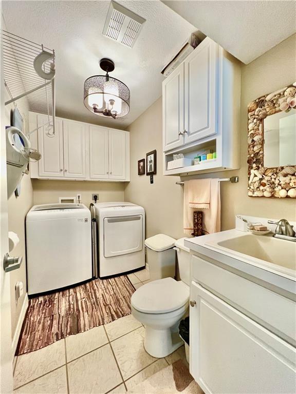 11 Saint Andrews Lane Holiday Island Unit 9, Holiday Island, AR 72631 - bathroom with washing machine and dryer, vanity, tile patterned flooring, and a textured ceiling
