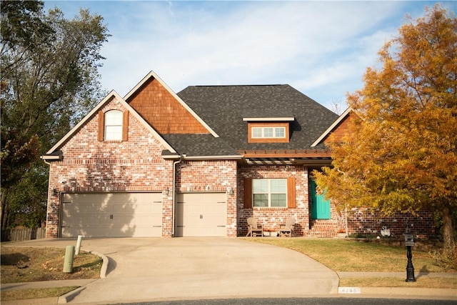 craftsman inspired home featuring brick siding, a shingled roof, a front yard, driveway, and an attached garage