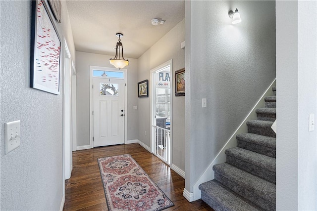 foyer featuring stairway, wood finished floors, baseboards, and a textured wall