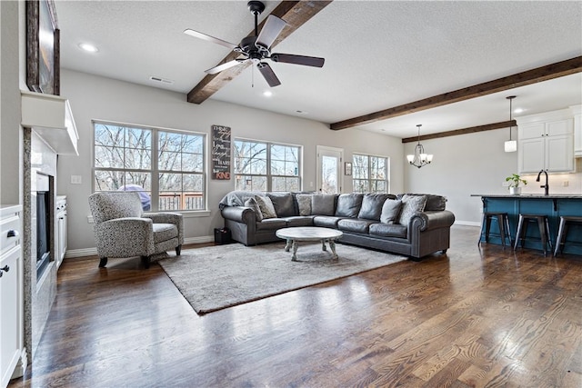 living room featuring beam ceiling, dark wood-style floors, a textured ceiling, and visible vents