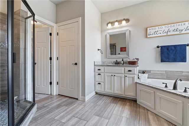 full bathroom featuring wood tiled floor, vanity, a bath, and a shower stall