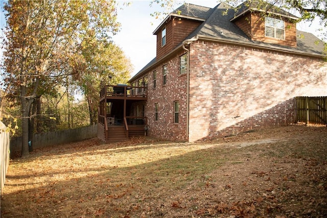 view of home's exterior featuring a fenced backyard, brick siding, and a wooden deck