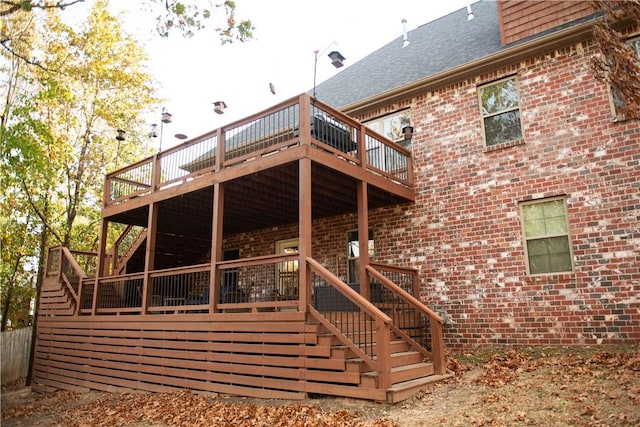 rear view of property with brick siding, a shingled roof, stairs, and a deck