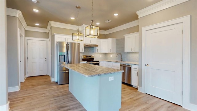 kitchen with under cabinet range hood, appliances with stainless steel finishes, light wood-style floors, white cabinetry, and a sink