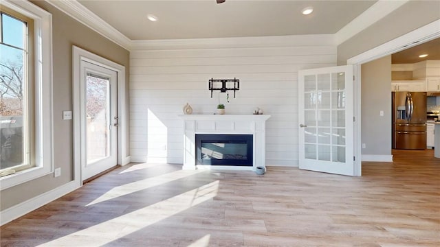 living room with light wood finished floors, baseboards, ornamental molding, recessed lighting, and a glass covered fireplace