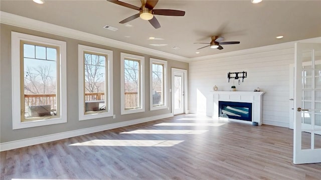 unfurnished living room with visible vents, a fireplace, wood finished floors, and crown molding