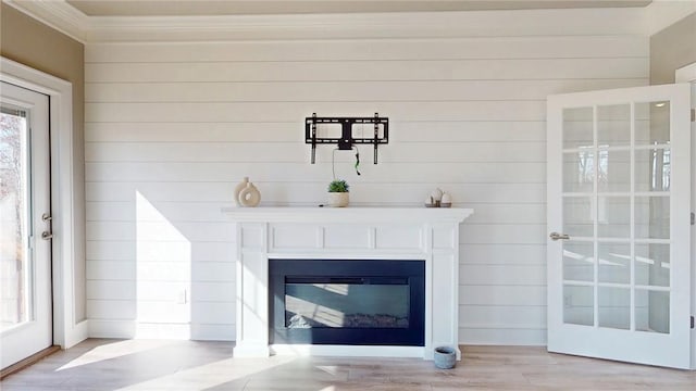 room details featuring a glass covered fireplace, crown molding, and wood finished floors