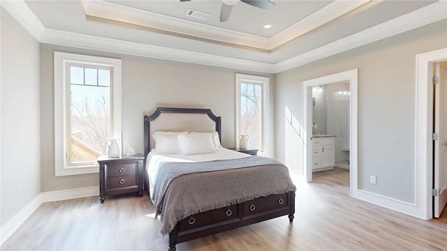 bedroom featuring a tray ceiling, light wood-style flooring, and visible vents