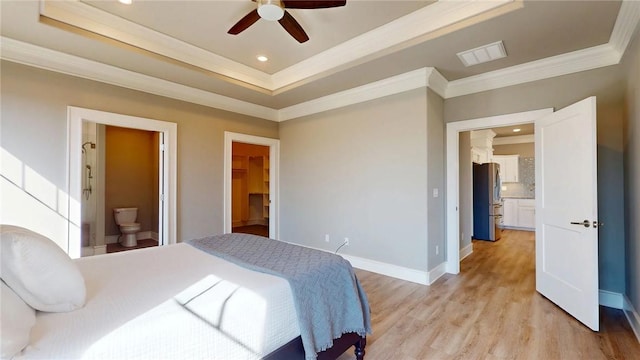 bedroom with a tray ceiling, visible vents, light wood-style flooring, and freestanding refrigerator