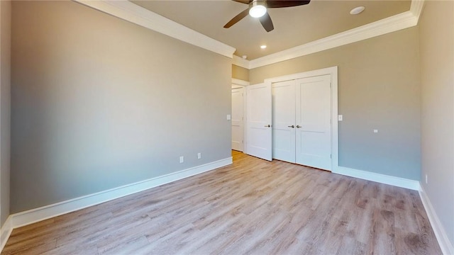 unfurnished bedroom with light wood finished floors, a closet, crown molding, and baseboards