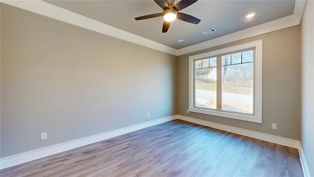 empty room with wood finished floors, baseboards, visible vents, and ornamental molding