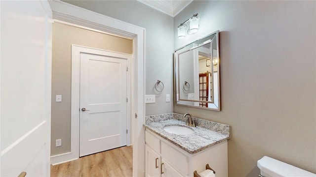 half bath with vanity, toilet, and wood finished floors