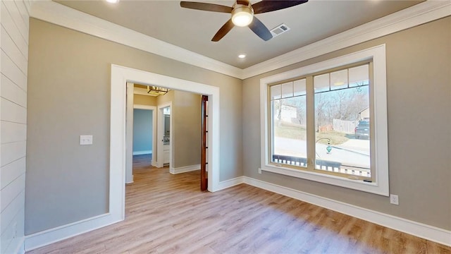 empty room featuring visible vents, baseboards, wood finished floors, and crown molding