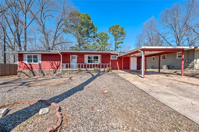 ranch-style home featuring fence, crawl space, covered porch, a carport, and driveway