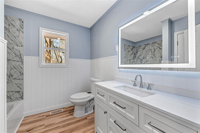 full bathroom with vanity, wood finished floors, a wainscoted wall, visible vents, and toilet