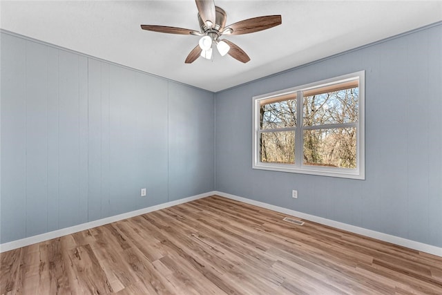 empty room with a ceiling fan, light wood-style flooring, baseboards, and visible vents