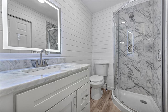 full bathroom featuring a marble finish shower, toilet, vanity, and wood finished floors