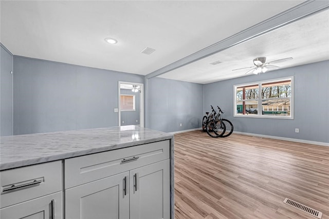 kitchen featuring visible vents, open floor plan, light wood-style flooring, and a ceiling fan