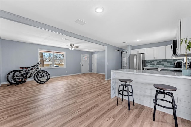 kitchen featuring white cabinetry, a breakfast bar area, a barn door, a peninsula, and stainless steel appliances