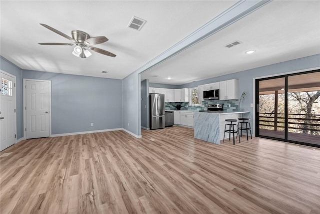 unfurnished living room featuring light wood finished floors, visible vents, and baseboards