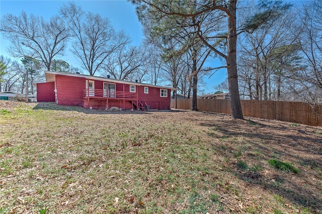 rear view of property featuring a yard and fence