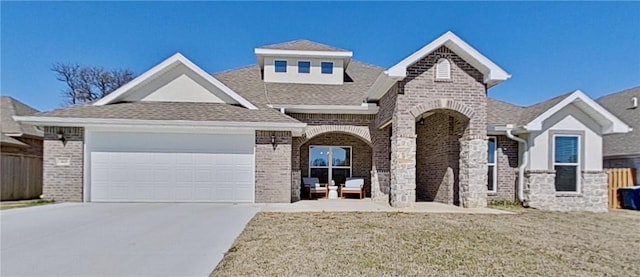 view of front of property featuring driveway, brick siding, roof with shingles, and an attached garage