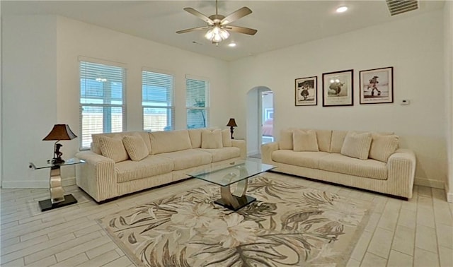 living room with visible vents, baseboards, light wood-style flooring, recessed lighting, and arched walkways