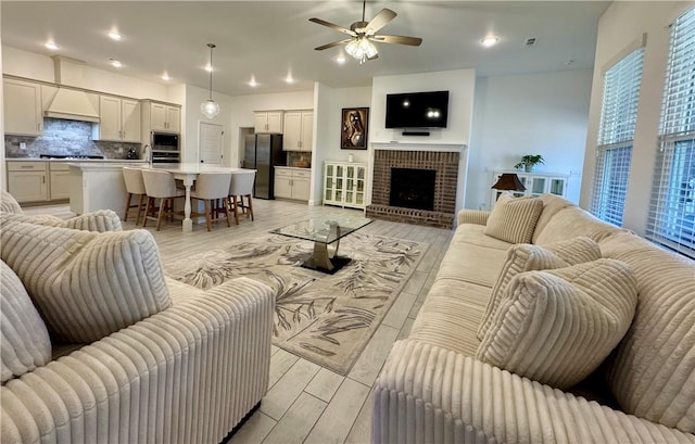 living room featuring a ceiling fan, recessed lighting, light wood-style floors, and a fireplace