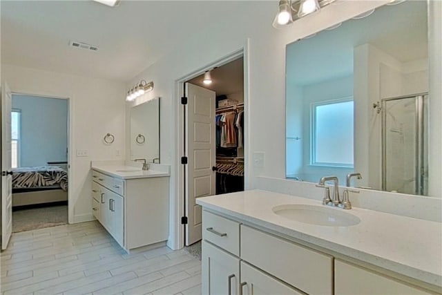 bathroom featuring a sink, visible vents, two vanities, and a shower stall