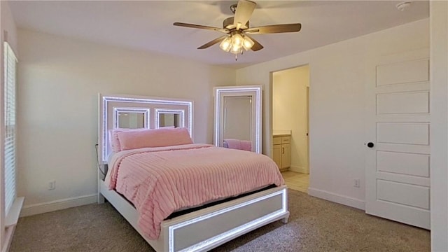 bedroom featuring light colored carpet, ensuite bath, baseboards, and ceiling fan