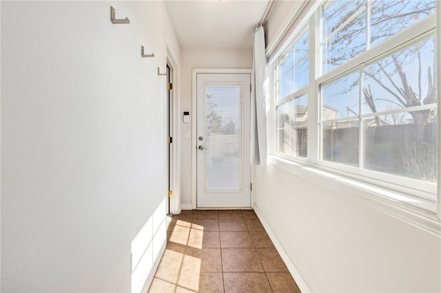 doorway to outside featuring light tile patterned floors and baseboards