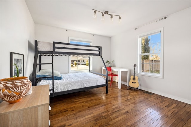 706 NW B St, Bentonville, AR 72712 - bedroom with baseboards, wood-type flooring, rail lighting, and visible vents