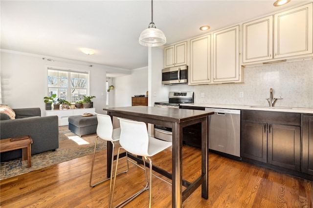 kitchen with light countertops, appliances with stainless steel finishes, light wood-style floors, cream cabinetry, and a sink