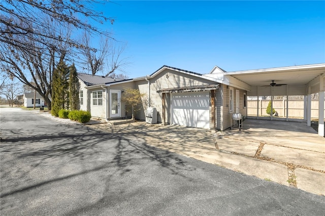 view of front facade featuring an attached garage, fence, driveway, and metal roof