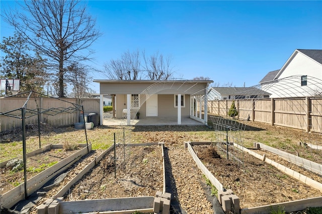 back of property with a vegetable garden, a patio area, and fence