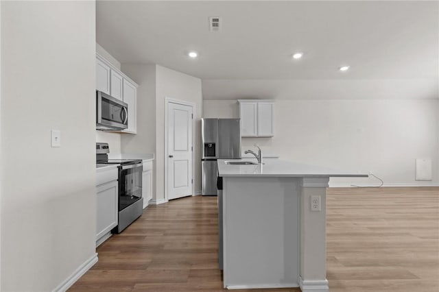 1317 Chavis St, Gentry, AR 72734 - kitchen featuring appliances with stainless steel finishes, a center island with sink, light wood-style floors, white cabinetry, and recessed lighting