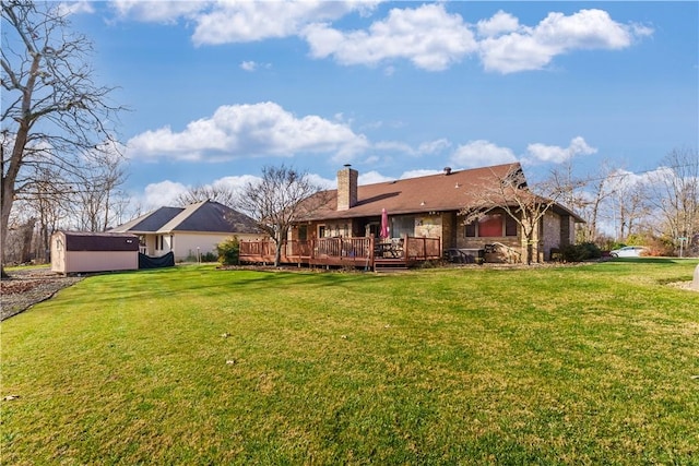 back of house featuring an outdoor structure, a lawn, a chimney, and a wooden deck