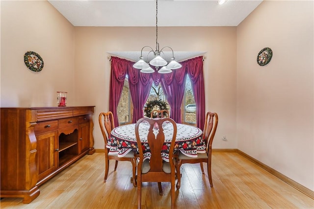 dining area featuring an inviting chandelier, light wood-style flooring, and baseboards