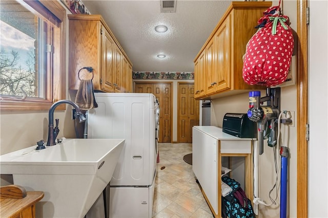 laundry area featuring visible vents, washer / dryer, cabinet space, a textured ceiling, and a sink