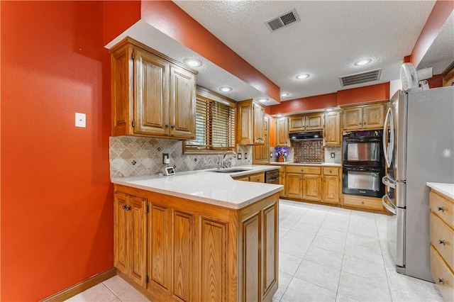 kitchen with visible vents, a peninsula, freestanding refrigerator, and a sink