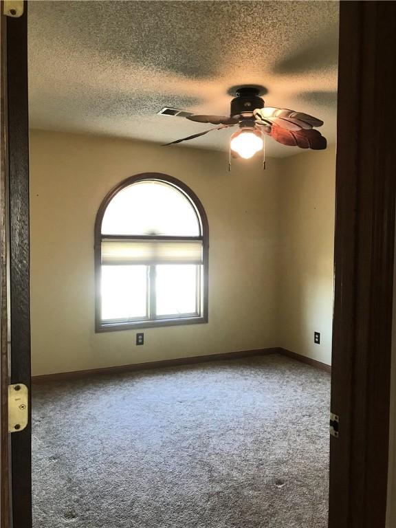 carpeted empty room featuring baseboards, a textured ceiling, and ceiling fan