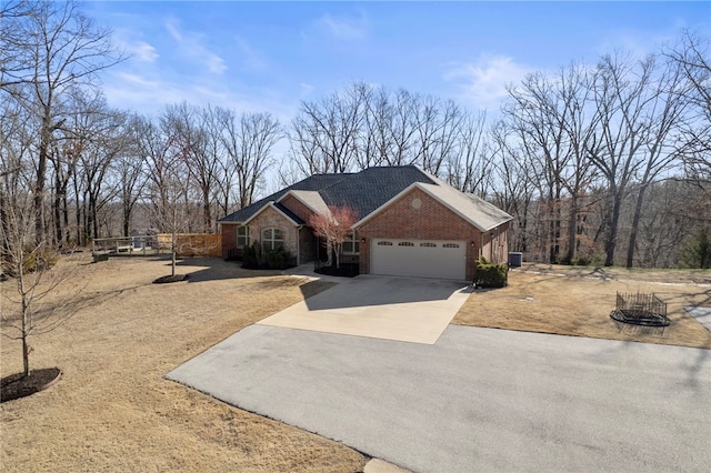 ranch-style house featuring fence, central AC, concrete driveway, a garage, and brick siding