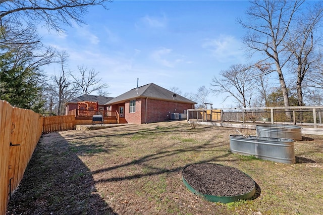 view of yard featuring central air condition unit, a wooden deck, and a fenced backyard