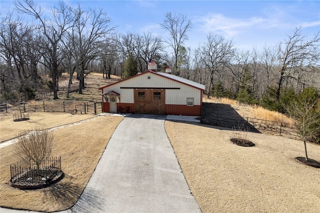 view of front of home featuring a garage, an outbuilding, driveway, and fence