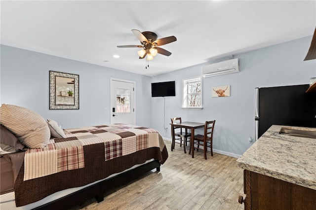 bedroom featuring a sink, a wall unit AC, light wood finished floors, baseboards, and ceiling fan