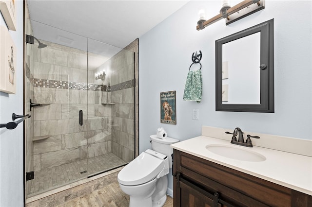 bathroom with vanity, toilet, wood finished floors, and a shower stall