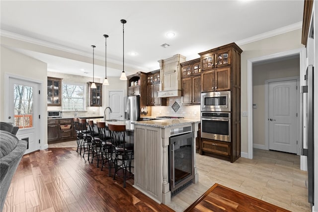 kitchen featuring backsplash, beverage cooler, light wood-type flooring, a kitchen breakfast bar, and stainless steel appliances