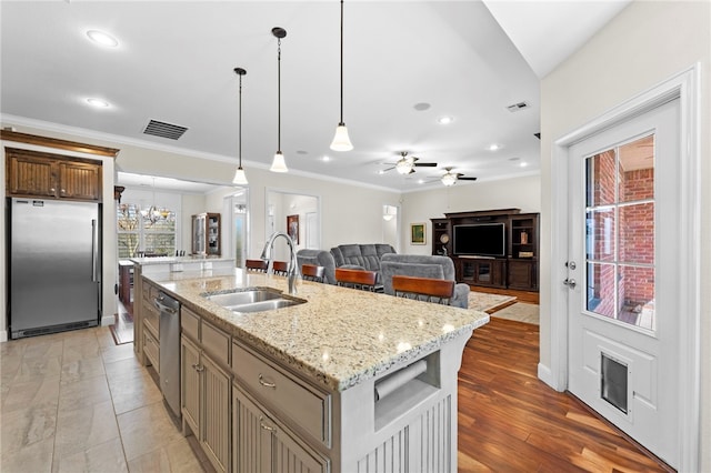 kitchen with visible vents, an island with sink, a sink, decorative light fixtures, and stainless steel appliances